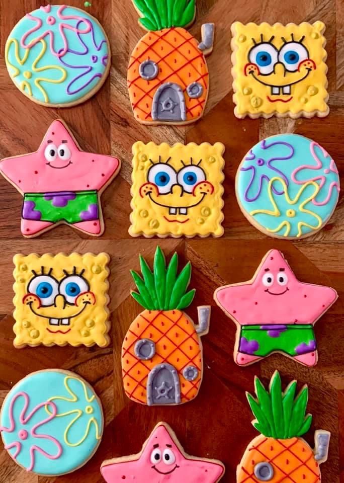 some decorated cookies are on a wooden table with pineapples and starfishes