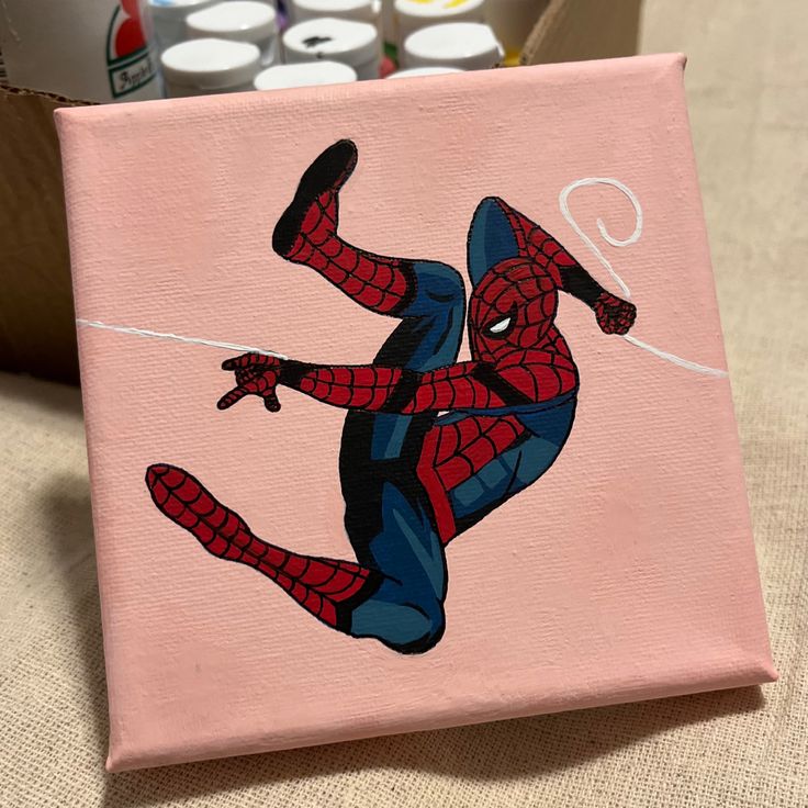 a painting of a spider man on a pink canvas with cans of soda in the background