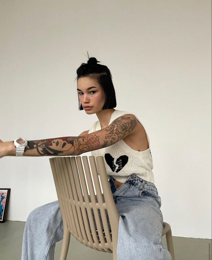 a woman sitting in a chair with tattoos on her arm