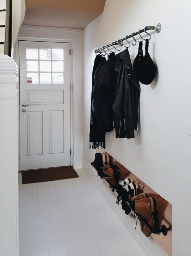 a coat rack with hats and purses hanging from it's hooks next to a white door