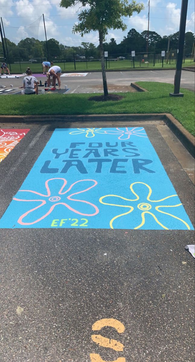 some people are sitting on the grass and playing with chalk