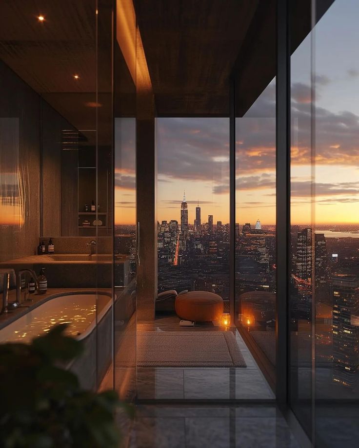 a bathroom with a bathtub, sink and large windows overlooking the city at sunset