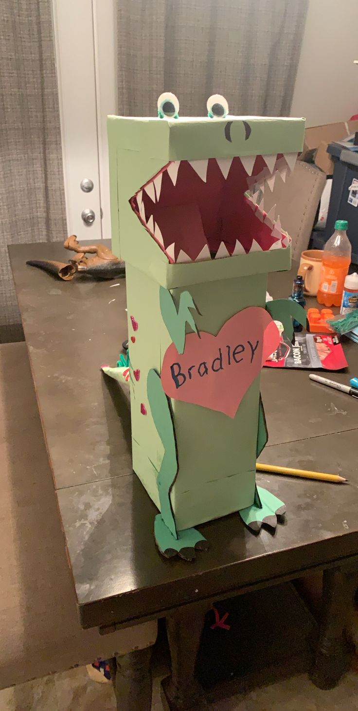 a cardboard box shaped like a dinosaur with its mouth open and tongue out, sitting on top of a table