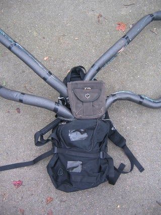 the back pack is sitting on the ground next to the bike's handlebars