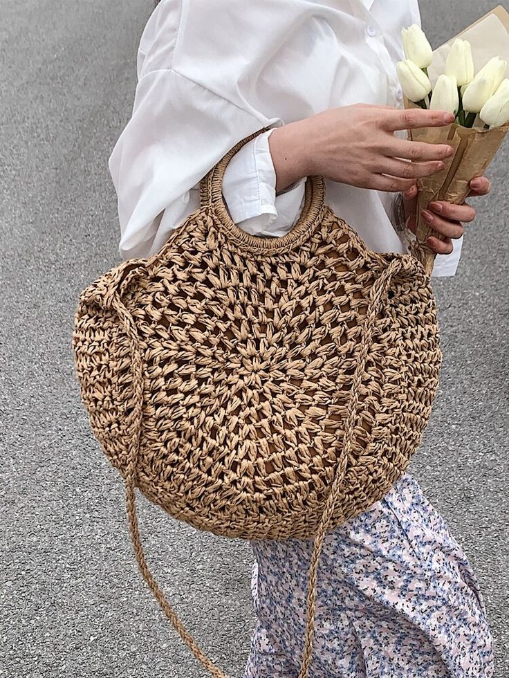 a woman carrying a straw bag with flowers in it