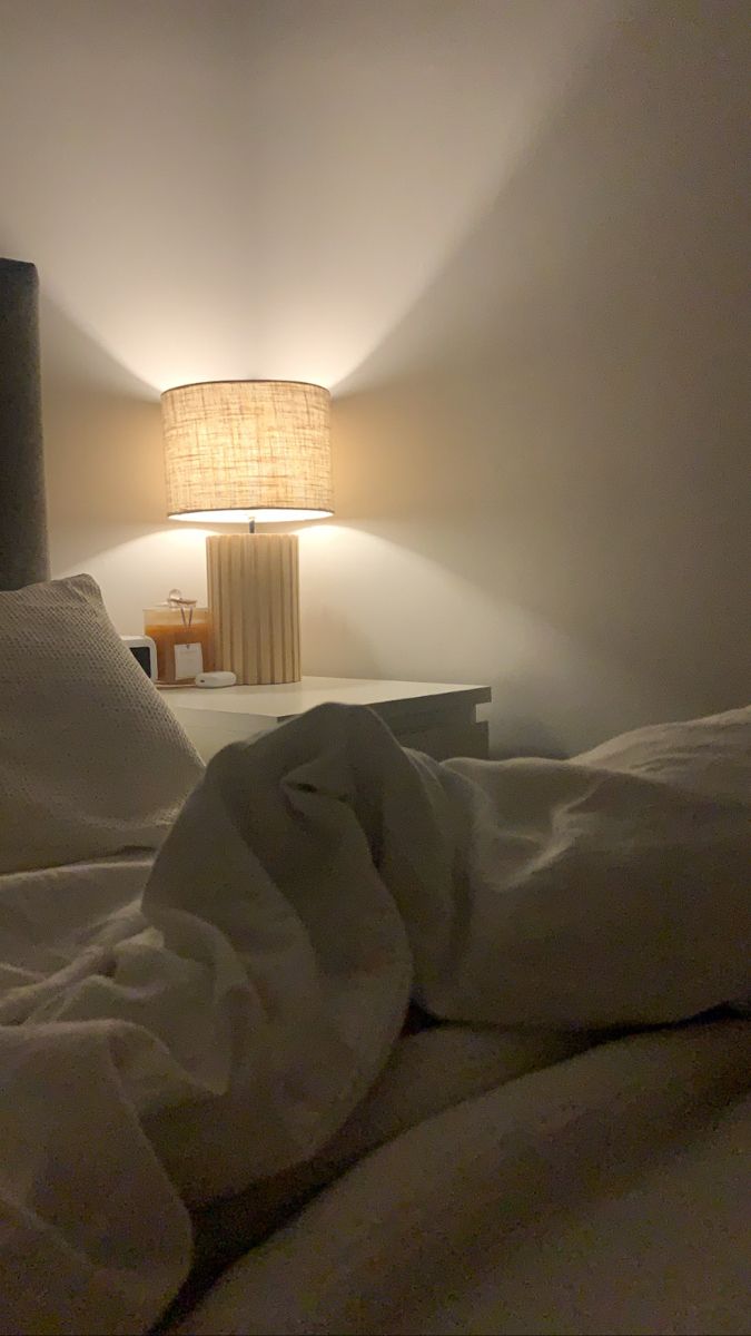 an unmade bed with white sheets and a lamp