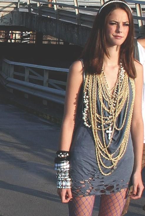 a woman in tights is standing on a skateboard with chains around her neck