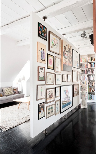 a living room filled with lots of framed pictures on the wall next to a couch