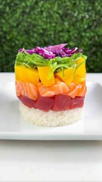 a white plate topped with sushi on top of rice covered in vegetables and sauce