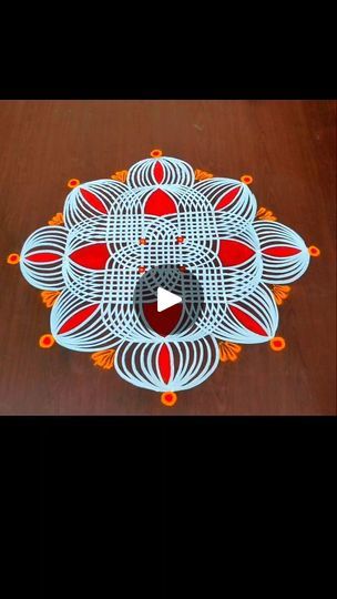 an intricately designed table top with red and orange designs on it, sitting on a wooden surface