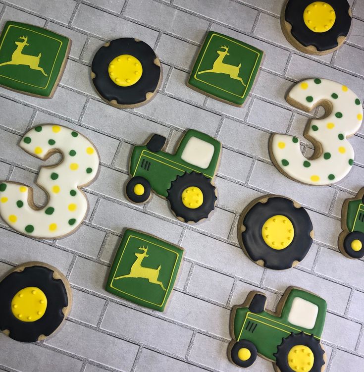 decorated cookies are arranged in the shape of tractors and tractor numbers on a brick wall