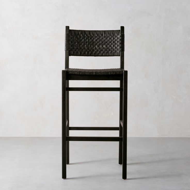 a black bar stool against a white wall