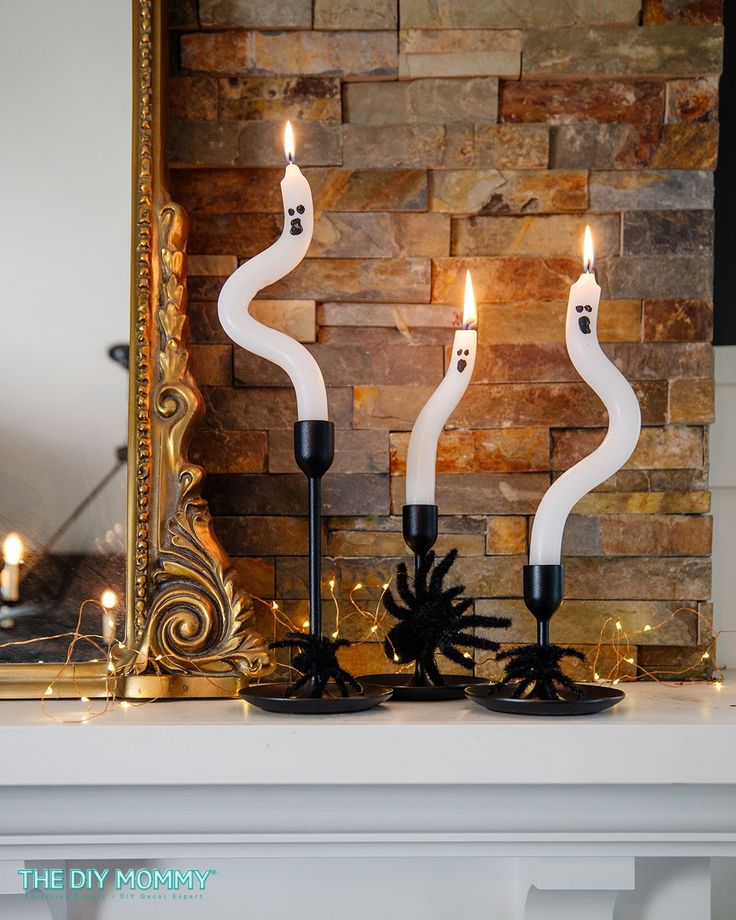 two candles sitting on top of a mantle next to a mirror