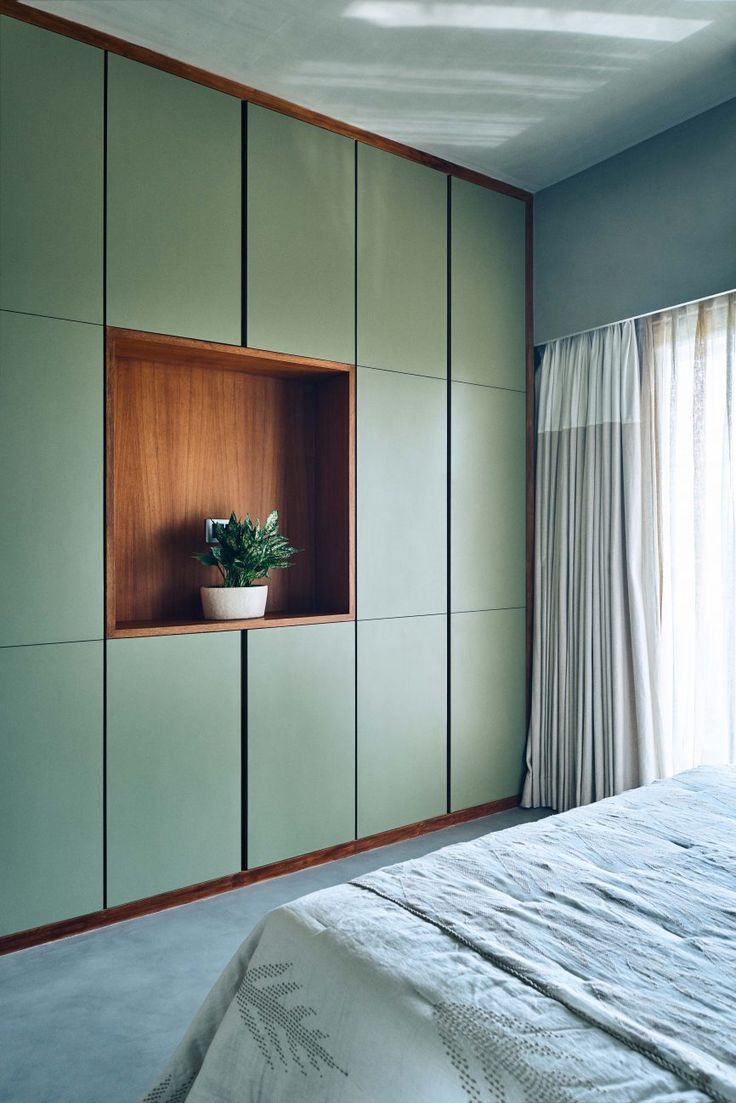 a bed sitting next to a window with a plant on top of the headboard