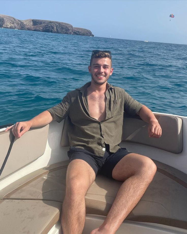 a man is sitting on the back of a boat in the blue water and smiling