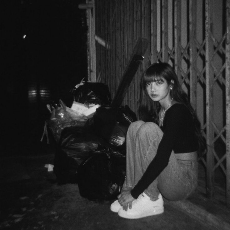 a woman sitting on the ground next to a pile of garbage