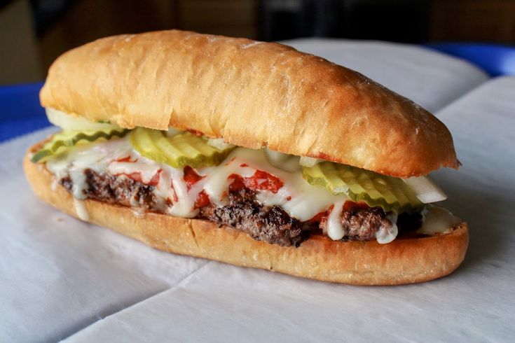 a close up of a sandwich with meat and cheese on a tableclothed surface