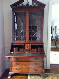 an old wooden china cabinet with glass doors and drawers on the front, in a living room