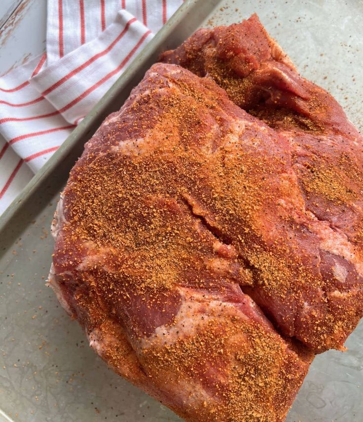 a piece of meat sitting on top of a pan covered in seasoning