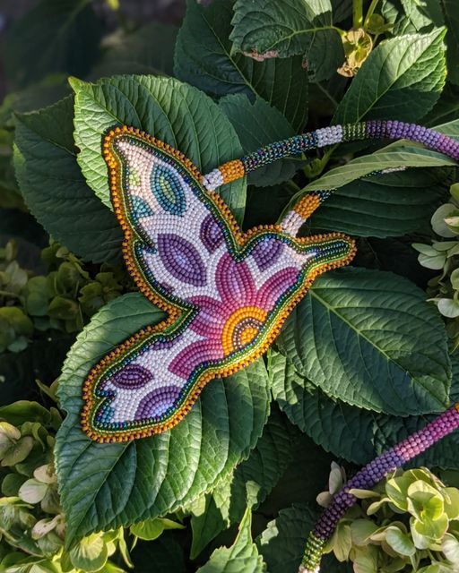 a colorful butterfly sitting on top of a green leaf covered plant with lots of leaves around it