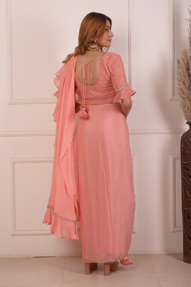 Peach chiffon pre-draped saree with lace and ruffle trimmed border. Paired with a matching lucknowi embroidered blouse with bell sleeves.
Components: 2
Pattern: Embroidered
Type Of Work: Lace, Lucknowi
Neckline: V Neck
Sleeve Type: Bell
Fabric: Chiffon
Color: Peach
Other Details: 
Back tie-up
Saree width: 40 inches
Blouse length: 15.5 inches
Occasion: Mehendi and Haldi - Aza Fashions Chiffon Blouse With Traditional Drape For Wedding, Elegant Semi-stitched Chiffon Blouse, Traditional Drape Chiffon Blouse For Wedding, Anarkali Chiffon Blouse Piece With Traditional Drape, Anarkali Style Chiffon Blouse With Traditional Drape, Anarkali Style Party Blouse Piece In Chiffon, Anarkali Style Chiffon Blouse Piece For Party, Festive Traditional Draped Chiffon Blouse, Festive Chiffon Blouse For Wedding