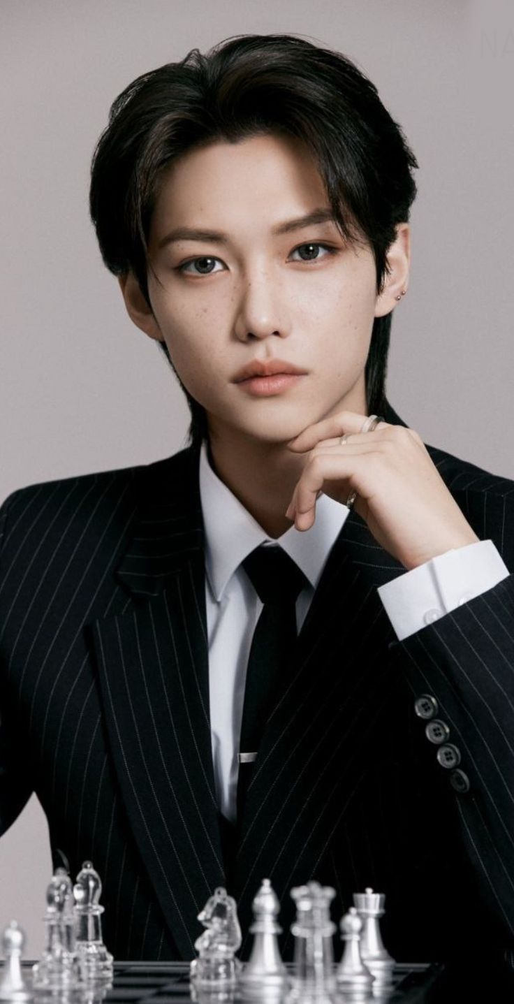 a woman in a suit sitting at a chess board