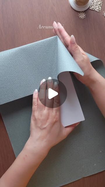 a woman is making a paper sculpture with her hands on the edge of a piece of paper