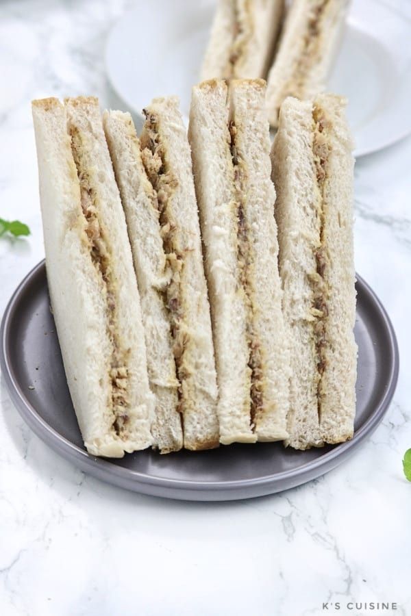 several sandwiches stacked on top of each other on a plate next to some green leaves