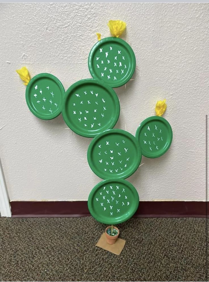 four green frisbees are arranged in the shape of a cactus