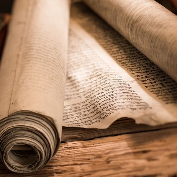 an open book on top of a wooden table next to a rolled up piece of paper