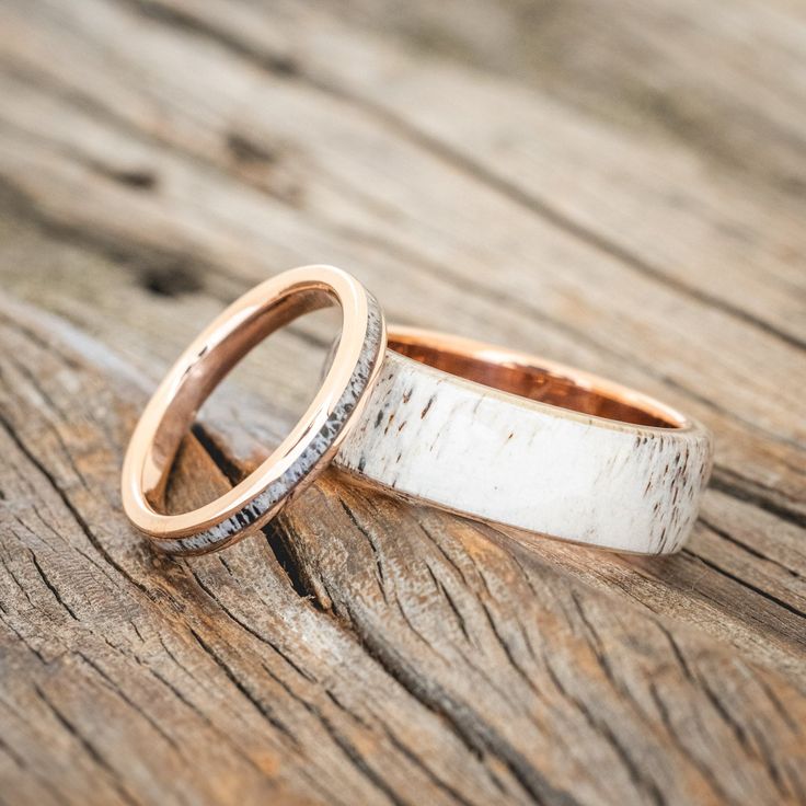 two wedding rings sitting on top of a wooden table