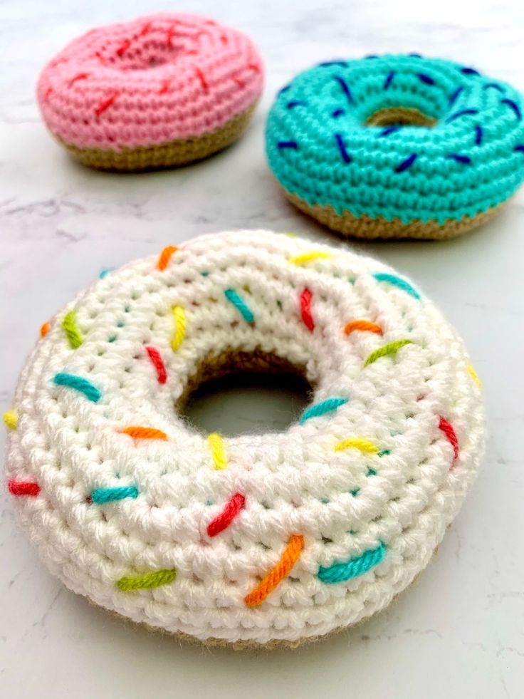 three crocheted donuts sitting on top of a white counter next to each other