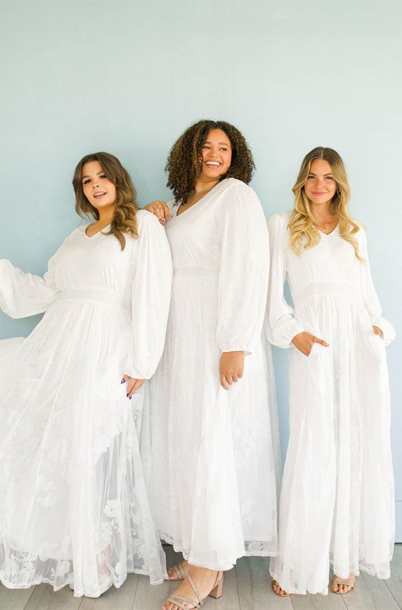 three women in white dresses standing next to each other