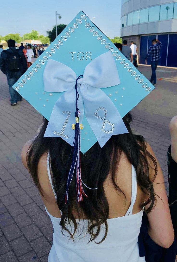 a girl wearing a blue graduation cap with a large bow on it's head