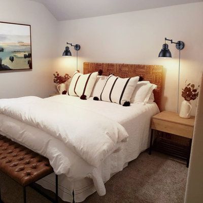 a bed with white sheets and pillows in a bedroom next to a painting on the wall