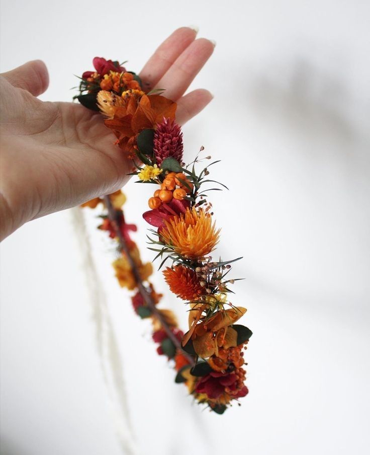 a hand holding an orange and red flower crown