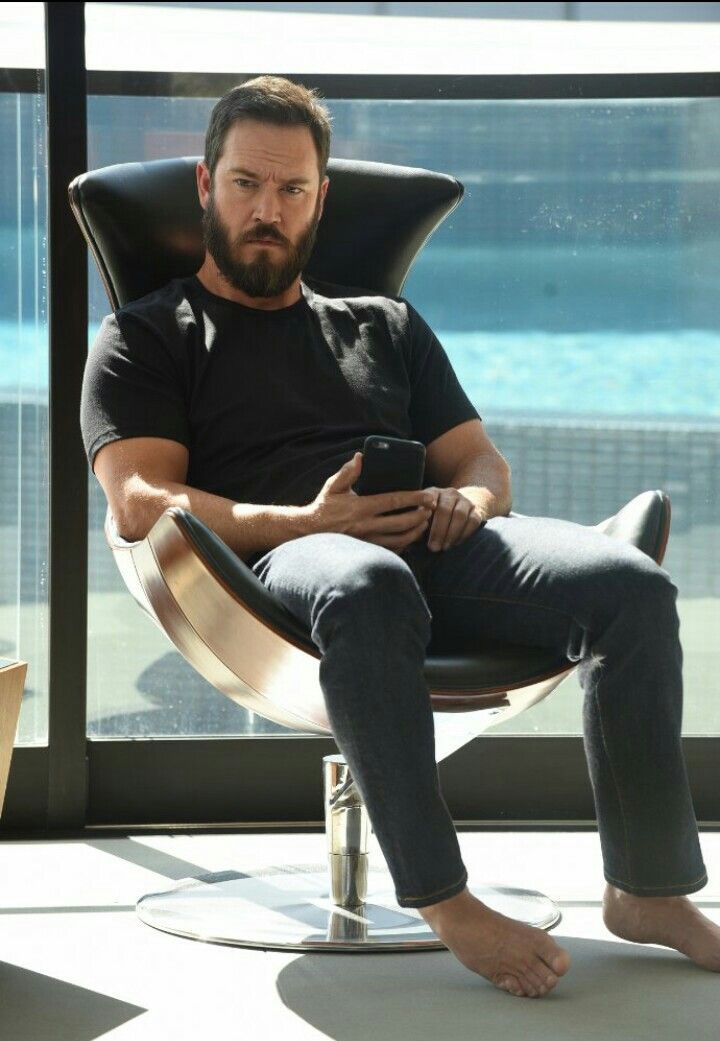 a man sitting in a chair looking at his cell phone