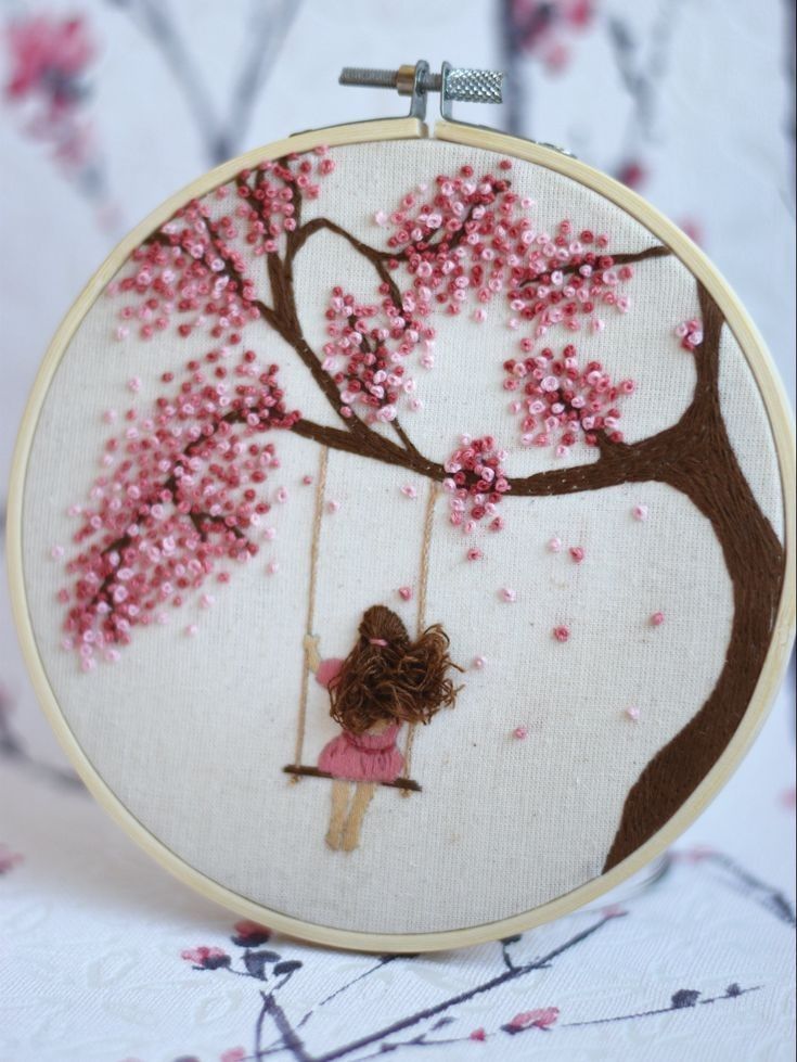 a girl is swinging on a cherry blossom tree with her hand embroideryed swinger