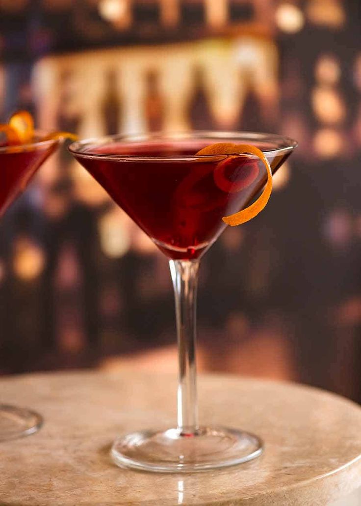 two martinis with orange peel garnish sit on a table