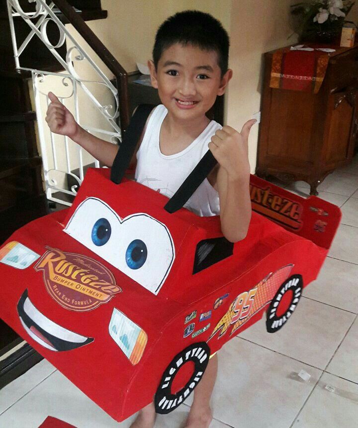 a young boy holding a cardboard box shaped like a car