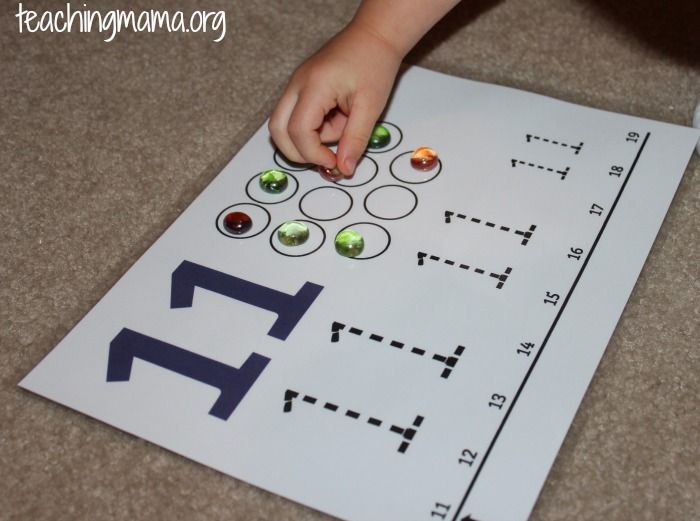 a child's hand is on top of a piece of paper with letters and numbers