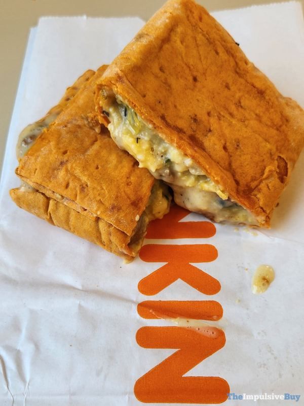 a sandwich sitting on top of a paper bag next to an orange and white sign