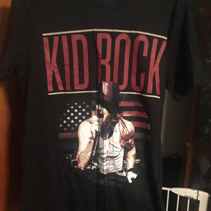 a black kid rock t - shirt with an american flag and a cowboy on it