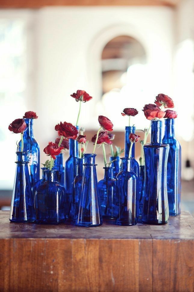 several blue vases with red flowers in them