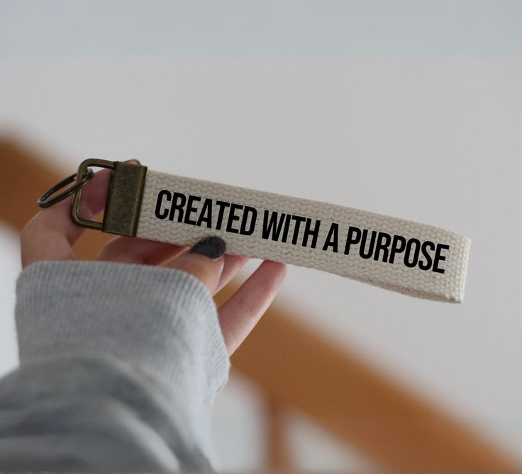 a person holding up a keychain with the words created with a purpose on it