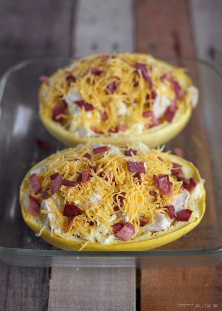 two pizzas covered in cheese and bacon sitting on a wooden table