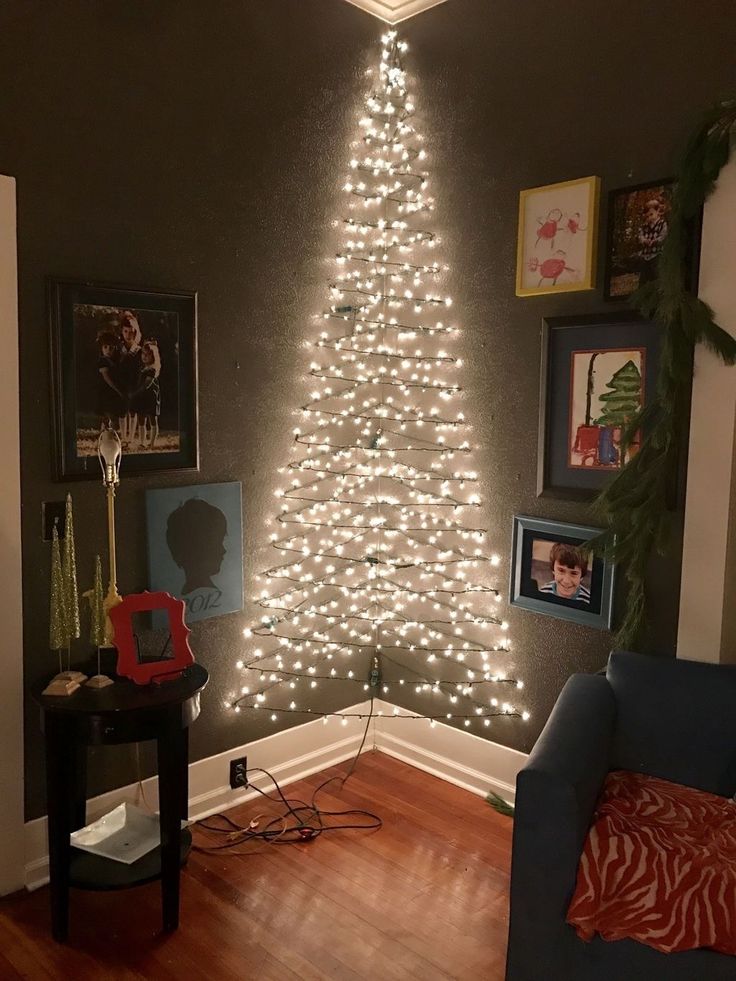 a living room with a lit christmas tree in the corner and pictures on the wall