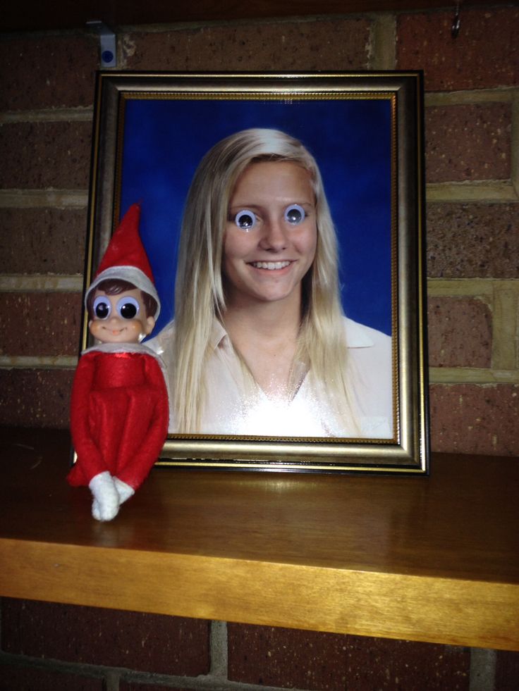 an elf with long blonde hair sitting next to a framed photo