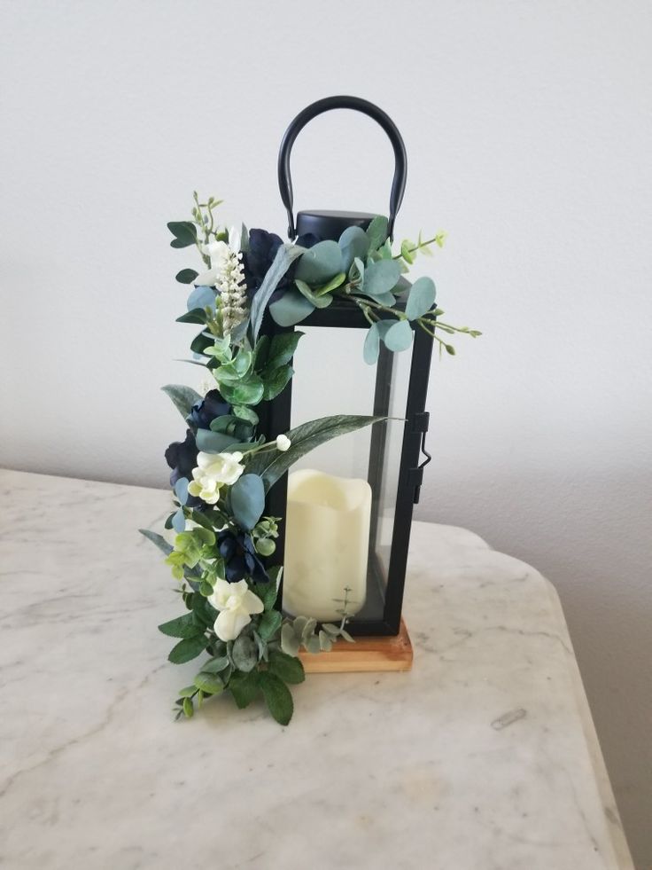 a candle and some greenery on a marble counter top in front of a white wall