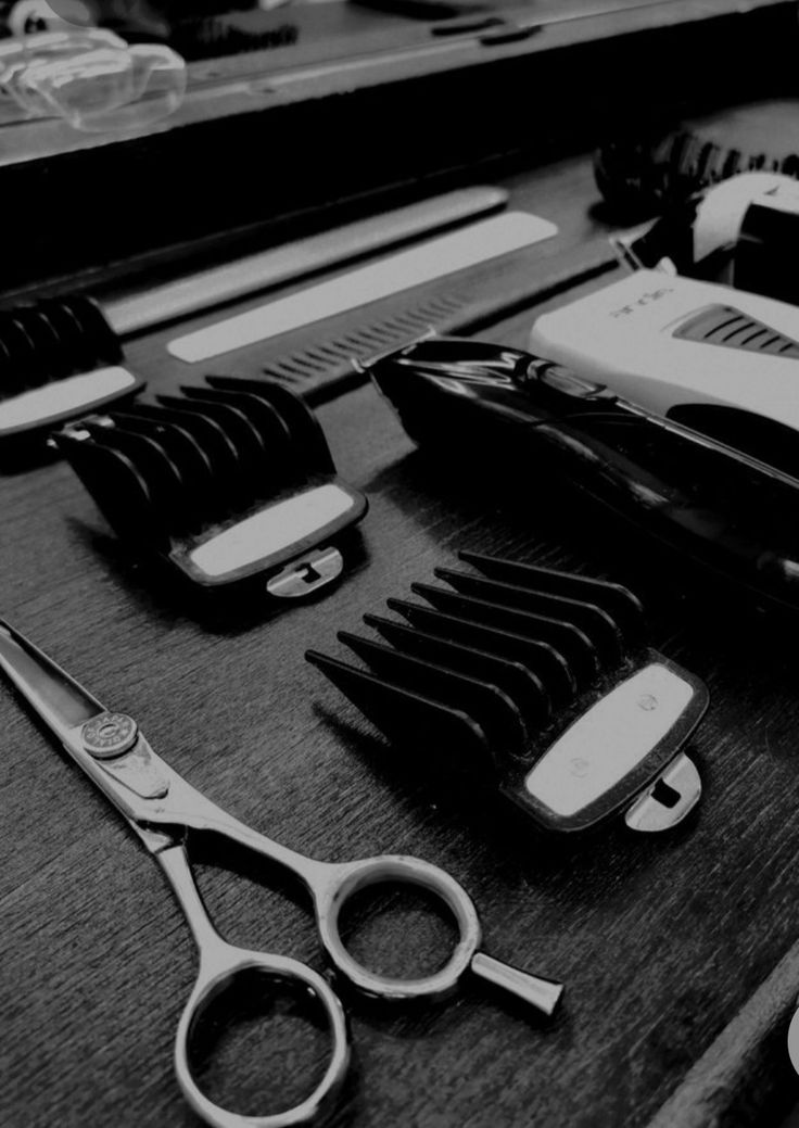 black and white photograph of scissors, combs, razor blades and other items on a table